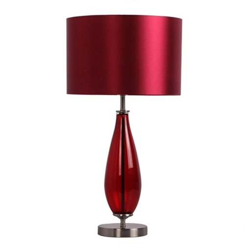 Lampu meja kaca rubi antik di samping tempat tidur dengan naungan kain merah